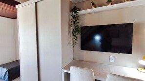 Moderni olohuone, jossa on seinälle asennettu taulutelevisio, sohva ja pieni pöytä, jossa on lamppu.