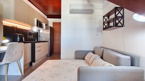 A compact living space with a kitchenette, a sofa, and a dining area. - Carneiros Atlantico Beira-mar - Proximo da Igrejinha (Tamandaré)