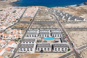 A coastal residential area with a central swimming pool surrounded by modern buildings. - Home2Book Bright Abades Apt, Pool & Gym (Abades)