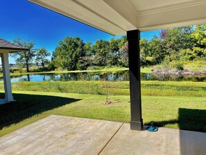 A covered patio area with a view of a pond and surrounding greenery. - The Cozy Pond House — Spacious, Cozy, Peaceful (Olive Branch)