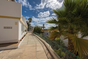 A narrow pathway flanked by buildings, a sign indicating 'BLOQUE 4', and a palm tree. - Home2Book Morro Jable Coastal Studio by the Beach (Solana Matorral)