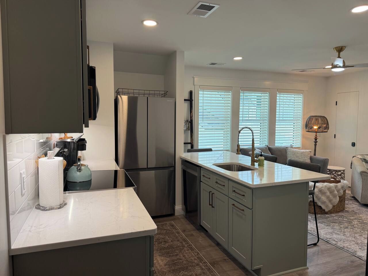 A modern kitchen with a central island, stainless steel appliances, and a dining area with a sofa and table.