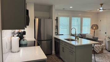 A modern kitchen with a central island, stainless steel appliances, and a dining area with a sofa and table.