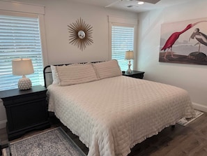A bedroom with a bed, nightstands, a lamp, a wall clock, and a painting. - Private Downtown Bluffton Carriage House (Bluffton)