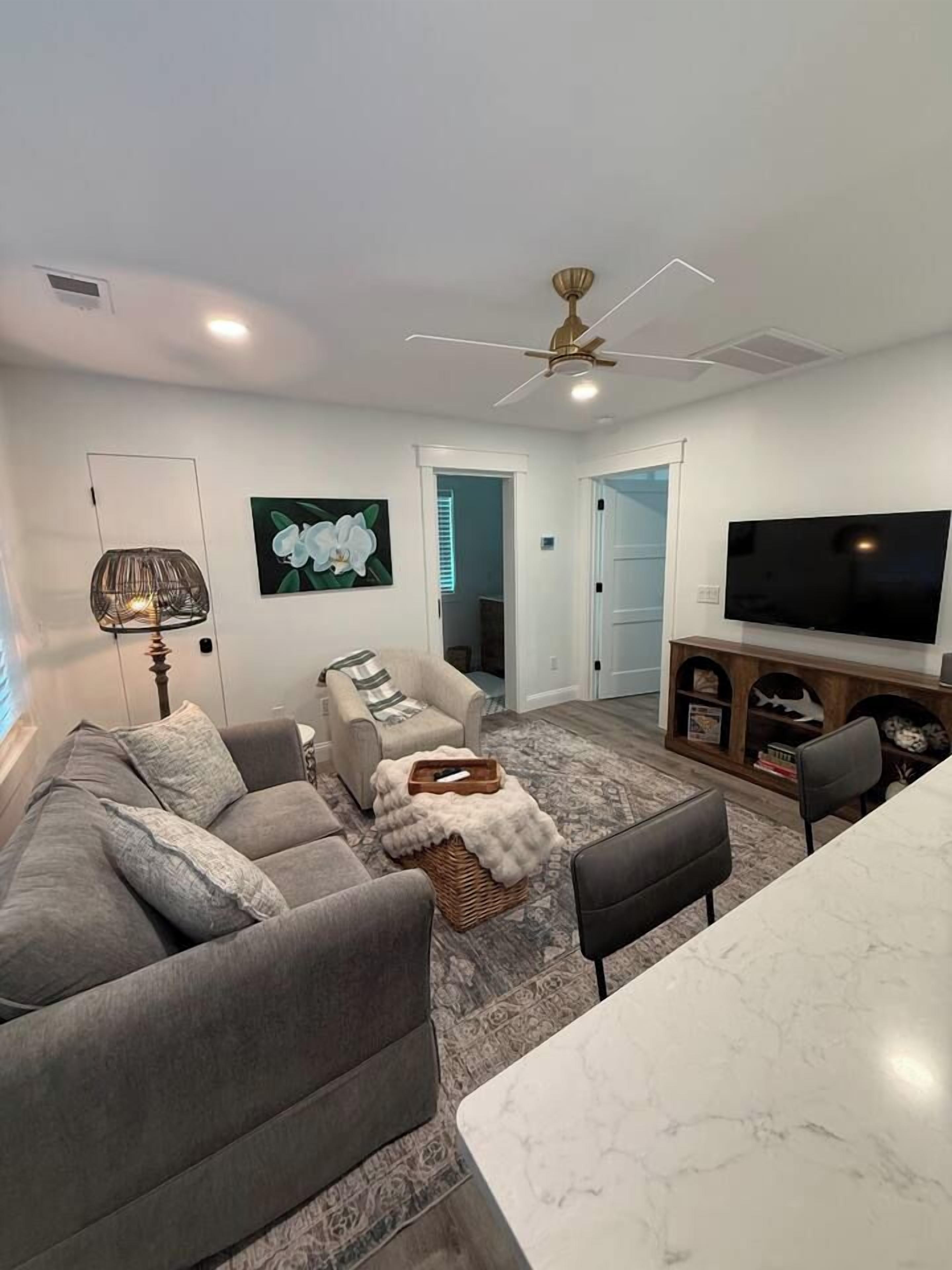 A modern living room with a sofa, armchair, and a flat-screen TV.