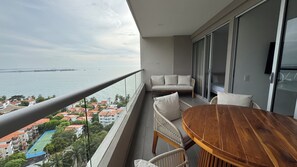 Uma varanda com vista para o mar, uma mesa de madeira e um sofá.