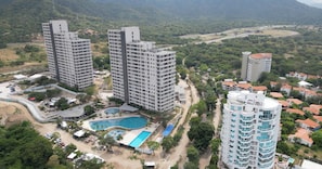 Um complexo de edifícios residenciais altos, com várias varandas, piscina e área ajardinada ao redor.
