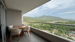 Un balcon avec une table et des chaises, donnant sur un paysage montagneux.