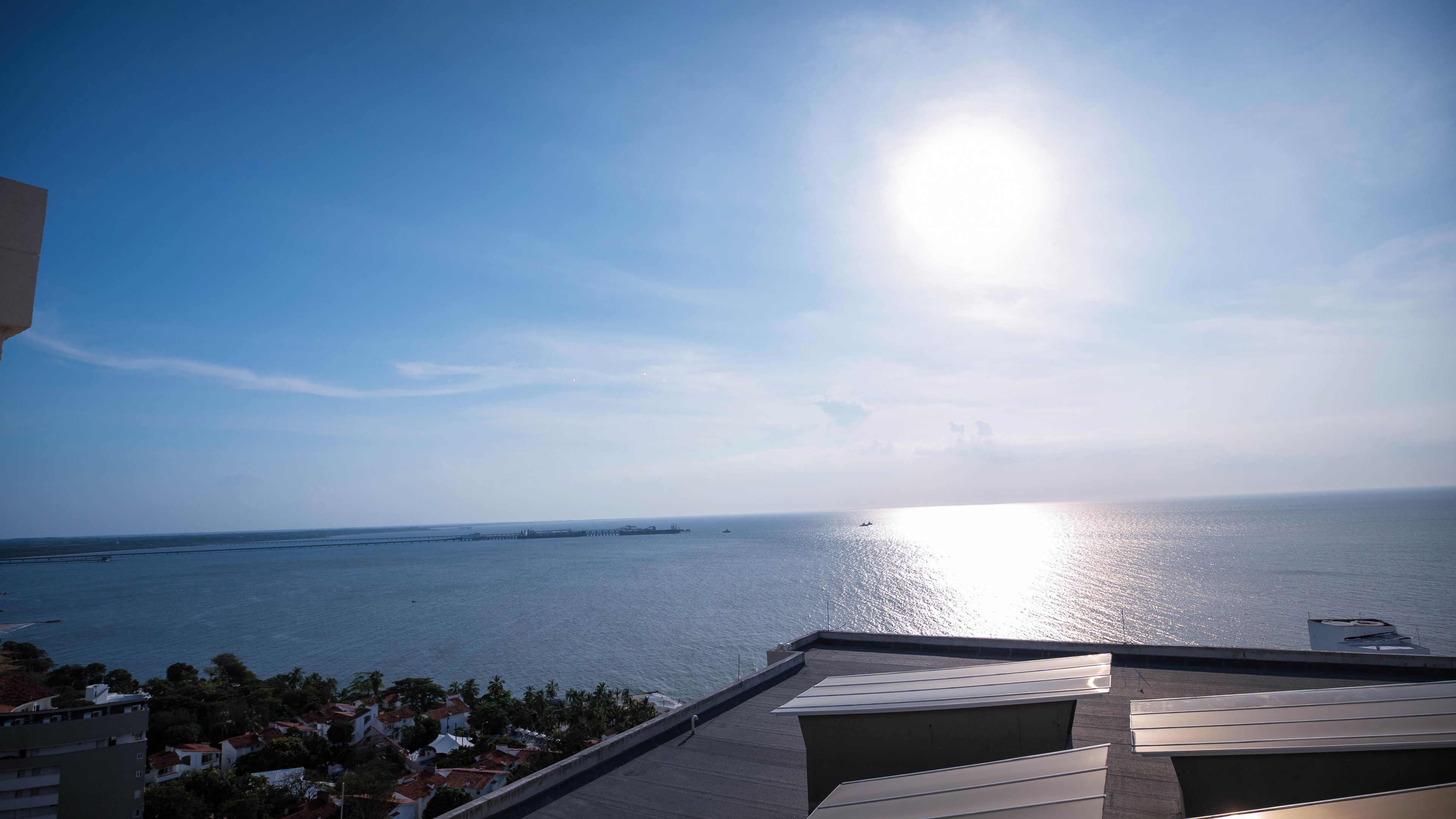 Vista costera con cielo despejado, mar tranquilo y una costa lejana.