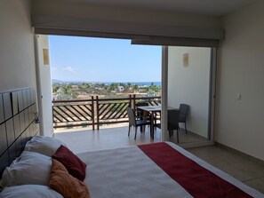 Ein Schlafzimmer mit Bett, Balkonblick und Tisch mit Stühlen.
