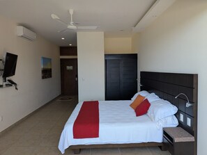 Ein Schlafzimmer mit einem Bett, einem Fernseher und einem Deckenventilator.