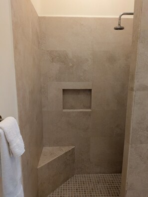 Eine Dusche mit integrierter Sitzbank und einer kleinen Ablage.