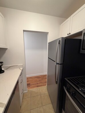 A compact kitchen with white cabinets, a black refrigerator, and a stove. - Modern Capitol Hill Location 1 Br apartment - Unit #4 (Washington)