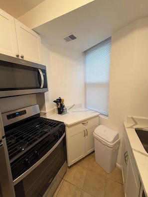 A compact kitchen with a microwave, stove, and white cabinets. - Modern Capitol Hill Location 1 Br apartment - Unit #4 (Washington)