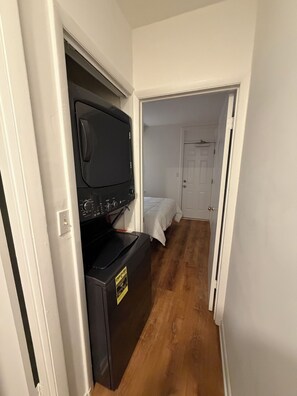 A narrow hallway with a black appliance, possibly a washer, and a bed in the adjacent room. - Modern Capitol Hill Location 1 Br apartment - Unit #4 (Washington)