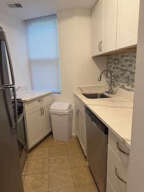 A compact kitchen with white cabinets, a stainless steel sink, and a tiled backsplash. - Modern Capitol Hill Location 1 Br apartment - Unit #4 (Washington)