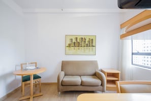 Ein modernes Wohnzimmer mit einem beigen Sofa, einem kleinen runden Tisch mit einem Stuhl und einem Bild an der Wand.