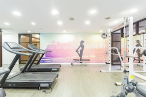 Ein Fitnessraum mit Laufbändern, einer Langhantelbank und einer Wand mit motivierenden Sprüchen.