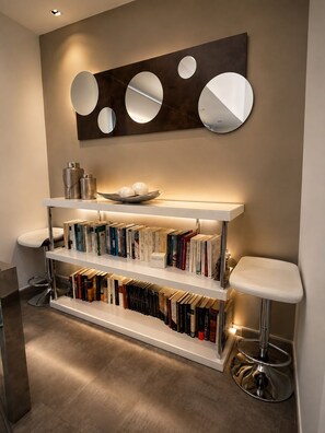 Un intérieur moderne avec une bibliothèque, deux tabourets de bar et un miroir fixé au mur.