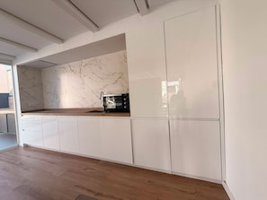 Une cuisine moderne avec des meubles blancs, un pare-feu en marbre et un plan de travail en bois.