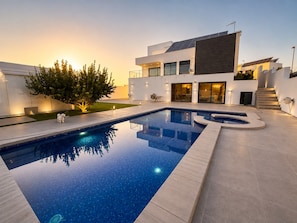 A modern house with a swimming pool, a staircase, and a tree.