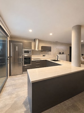 A modern kitchen with a large island, stainless steel appliances, and a minimalist design.