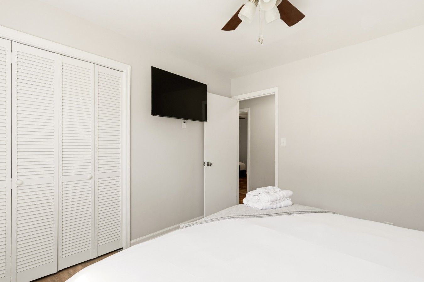 Ein Schlafzimmer mit einem Bett, einem an der Wand montierten Fernseher und einem Deckenventilator.