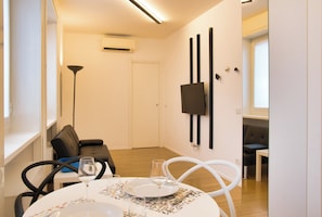 A dining area with a round table set for two, a sofa, and a TV mounted on the wall. - Milano Zara Urban Nest (Milan)