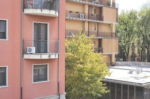 A multi-story building with balconies, air conditioning units, and a tree in the foreground. - Milano Zara Urban Nest (Milan)
