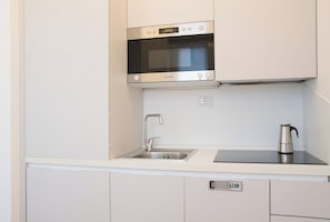 A modern kitchen with a built-in oven, stainless steel sink, and a kettle on the countertop. - Milano Zara Urban Nest (Milan)