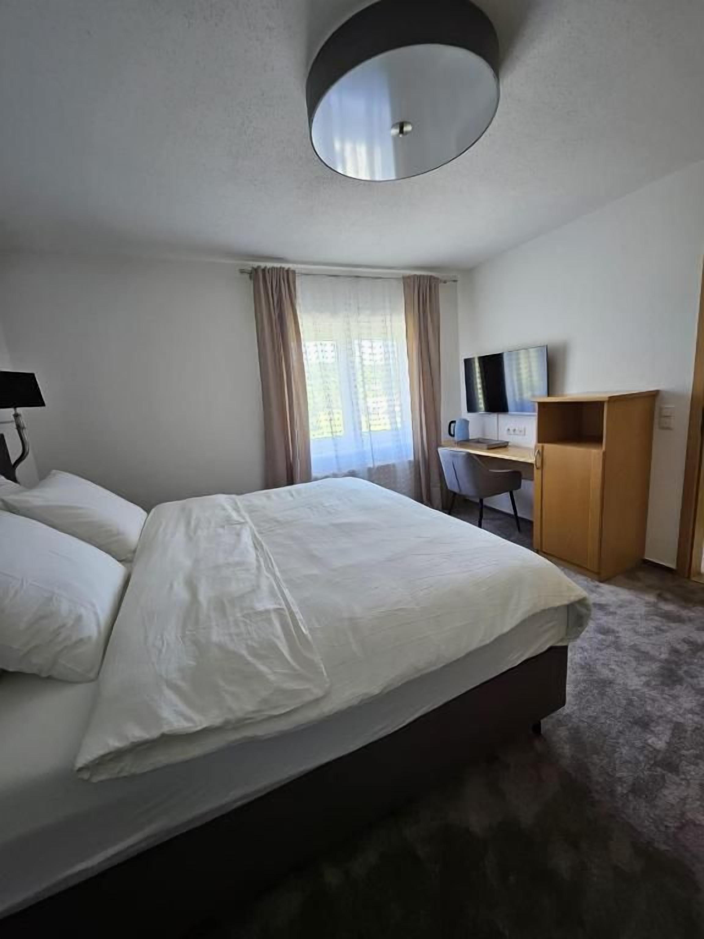 Een hotelkamer met een bed, een bureau, een stoel en een televisie.
