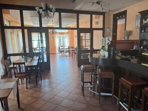 A restaurant with a bar area, dining tables, and chairs.