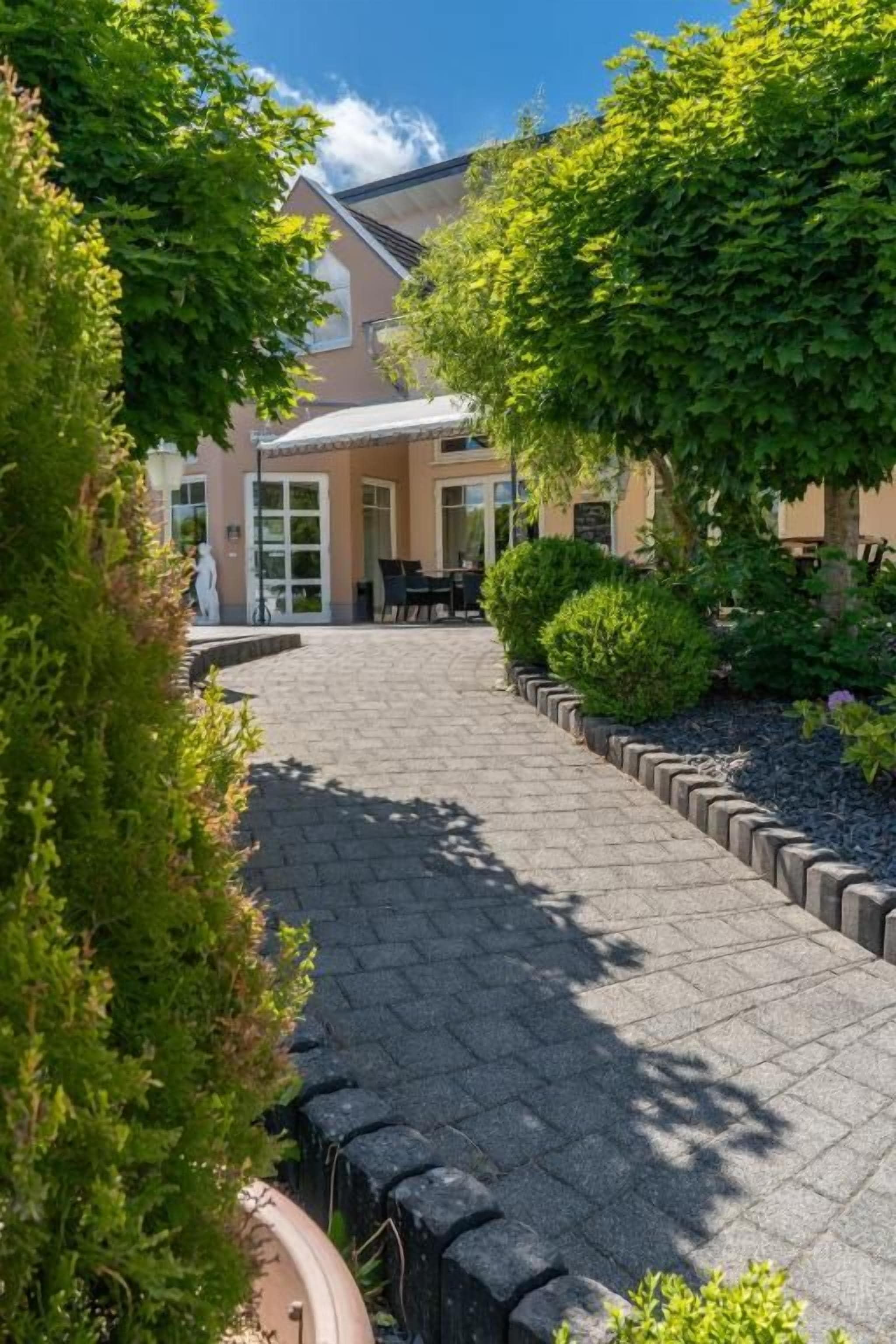 Ein gepflasterter Weg führt zu einem Gebäude mit einem Garten.