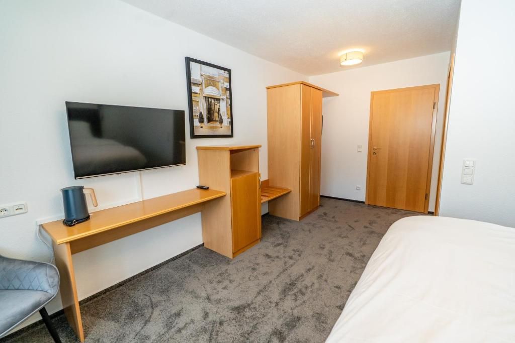 Una habitación de hotel con cama, escritorio, televisor y armario.