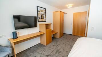 Una habitación de hotel con cama, escritorio, televisor y armario.