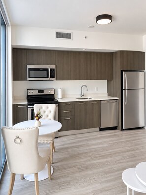 Eine moderne Küche mit Mikrowelle, Backofen und Kühlschrank. Es gibt einen Essbereich mit Tisch und Stühlen.