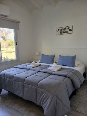 A neatly made bed with a grey duvet, two pillows, and rolled towels. - El Caldén Complex (San Luis)