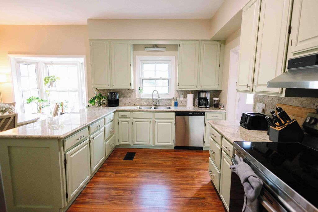 A kitchen with white cabinets, a dishwasher, a stove, and a sink.