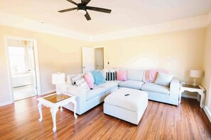 A living room with a sectional sofa, a coffee table, and a ceiling fan.