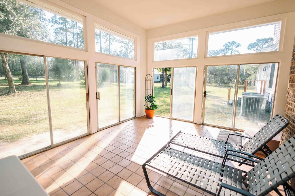 A sunlit room with large sliding glass doors, a potted plant, and two lounge chairs.