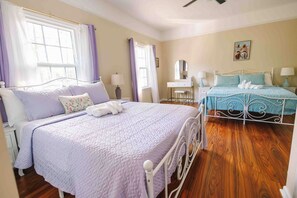 A bedroom with two beds, a desk, and a chair.