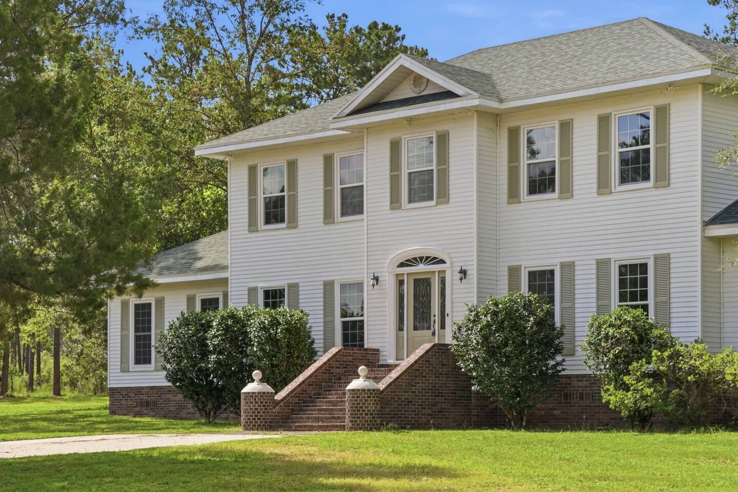 A two-story house with a front entrance, a brick porch, and a well-maintained lawn.