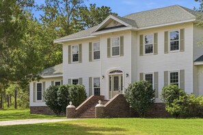 A two-story house with a front entrance, a brick porch, and a well-maintained lawn.