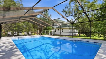 Une piscine couverte avec vue sur une maison et des arbres.