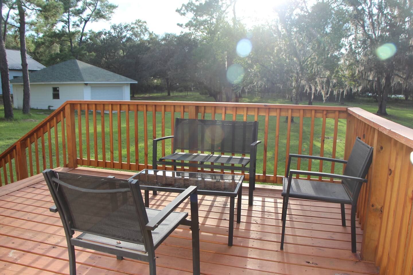 Une terrasse en bois avec une table et quatre chaises, entourée d’une balustrade en bois.