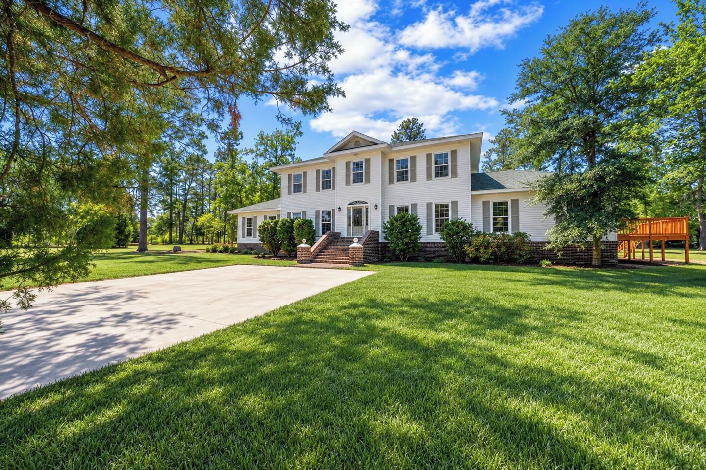 A two-story house with a front porch, a driveway, and a well-maintained lawn.