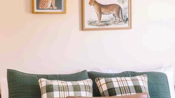 A bedroom with a bed, pillows, and two framed pictures of leopards on the wall.