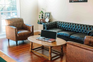 Un salón con un sillón de cuero marrón, un sofá de cuero negro y una mesa de centro de madera con un ordenador portátil.