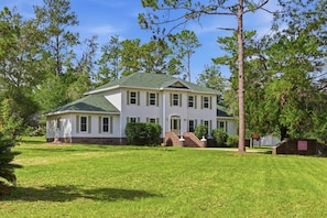 A two-story house with a green roof, a brick foundation, and a front porch. - Mabelle Estates | Historic Mansion • Pool • Farm (Gainesville)