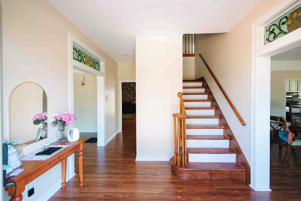 A hallway with a wooden staircase, a reception desk, and a door leading to another room.